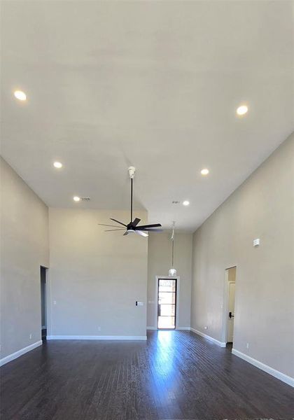 Unfurnished room featuring 15 ft high ceiling, dark wood finished floors, a ceiling fan, and recessed lighting Unfurnished room featuring 15 ft high ceiling, dark wood finished floors, a ceiling fan, and recessed lighting