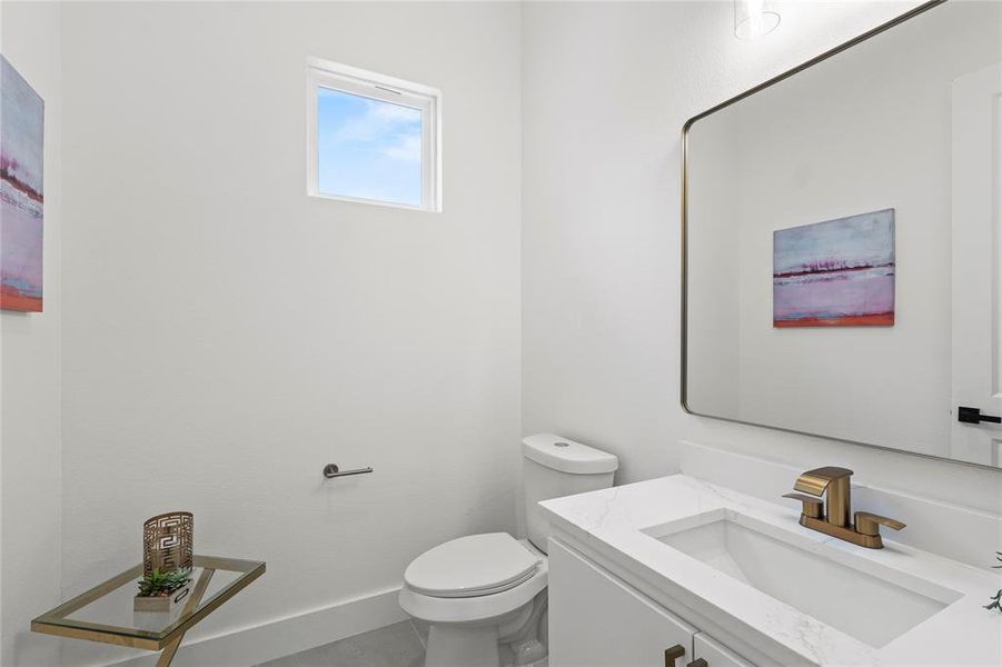 Half bath with baseboards, toilet, and vanity