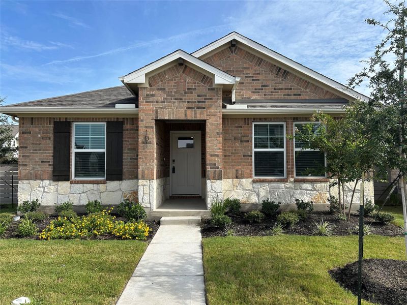 View of front facade featuring a front lawn, roof with shingles, and stone siding View of front facade featuring a front lawn, roof with shingles, and stone siding
