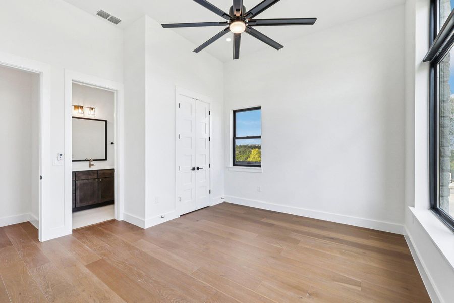 Unfurnished bedroom featuring light wood finished floors, connected bathroom, and a ceiling fan