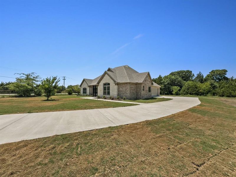 French country style house featuring a front yard, a garage, driveway, and brick siding French country style house featuring a front yard, a garage, driveway, and brick siding
