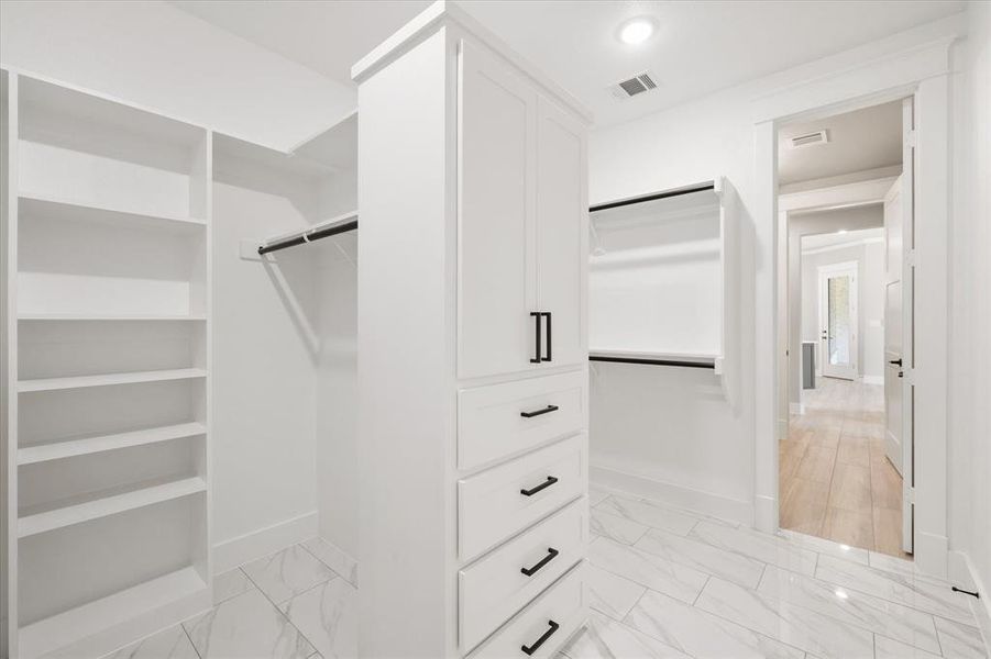 Custom white built-in cabinetry with black hardware, shelving, and hanging rods