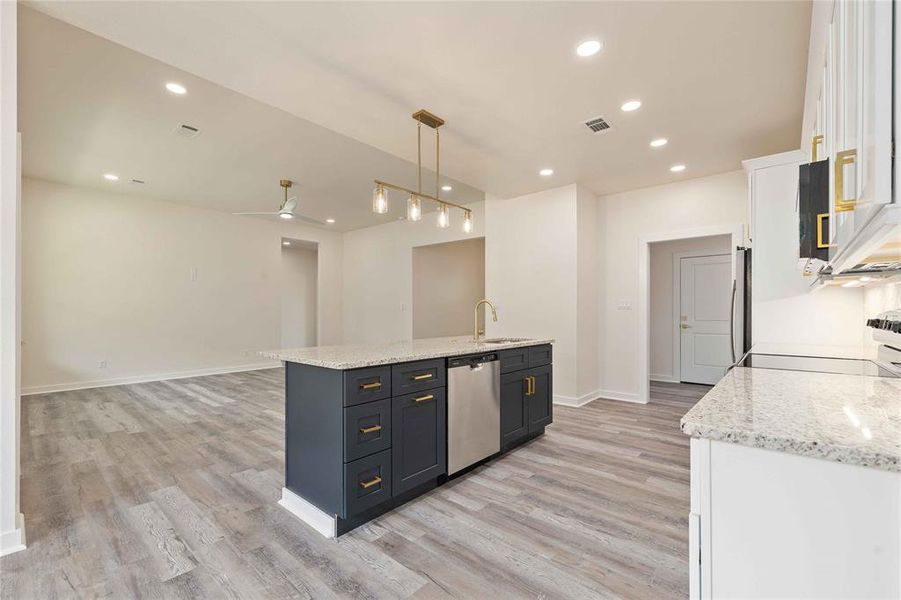 Kitchen featuring white cabinetry, light stone counters, hanging light fixtures, and recessed lighting Kitchen featuring white cabinetry, light stone counters, hanging light fixtures, and recessed lighting