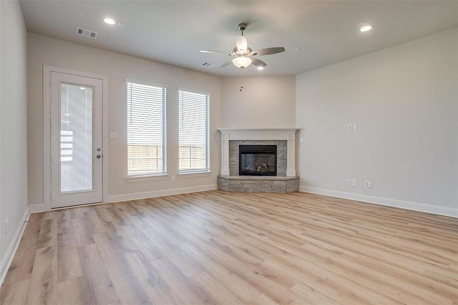 Unfurnished living room with a fireplace, light wood-type flooring, and ceiling fan