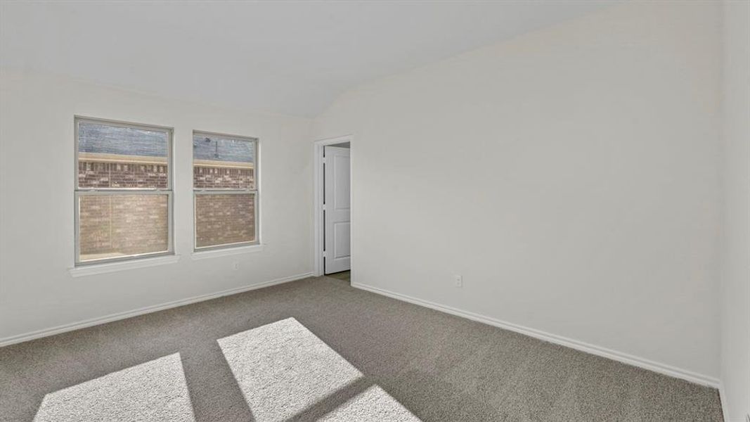Spare room with lofted ceiling and dark colored carpet