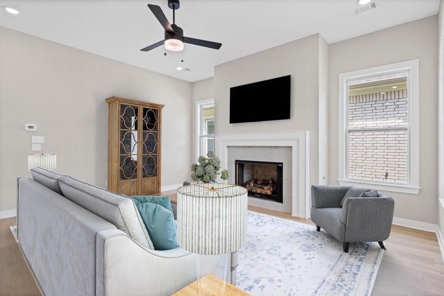 Living area featuring a fireplace with a white mantel, light wood-finish flooring, recessed lighting, and a ceiling fan Living area featuring a fireplace with a white mantel, light wood-finish flooring, recessed lighting, and a ceiling fan