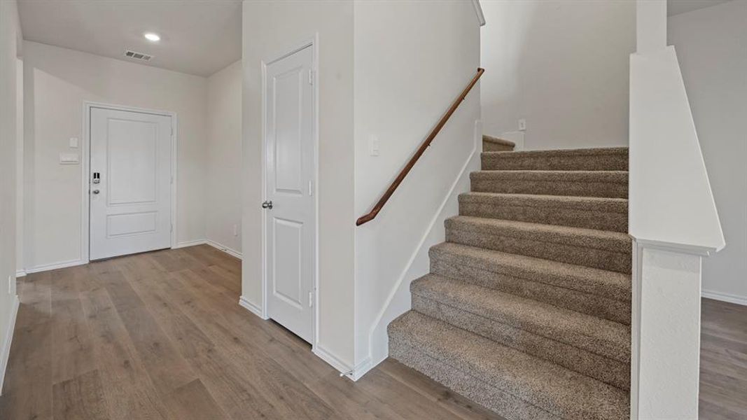Foyer entrance with wood finished floors, stairs, and recessed lighting