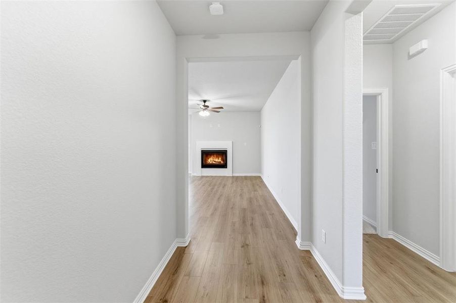 Hallway with wood-finish flooring, white baseboards, and light-toned walls