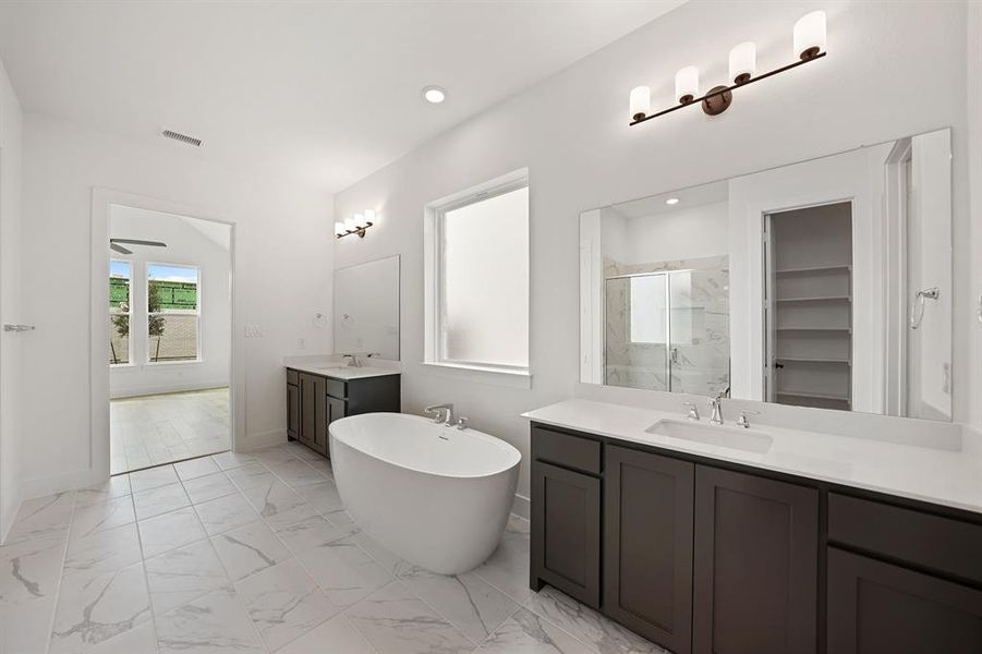 Bathroom with a marble finish shower, light marble finish flooring, two vanities, a freestanding tub, and a walk in closet Bathroom with a marble finish shower, light marble finish flooring, two vanities, a freestanding tub, and a walk in closet