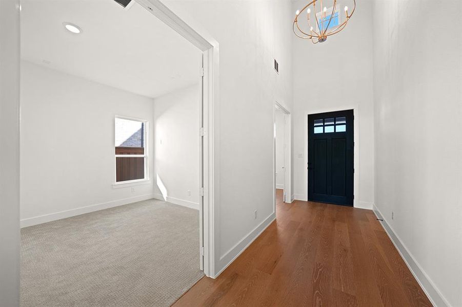 Foyer entrance featuring a chandelier, wood finished floors, plenty of natural light, a high ceiling, and recessed lighting Foyer entrance featuring a chandelier, wood finished floors, plenty of natural light, a high ceiling, and recessed lighting
