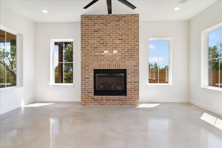 Unfurnished living room featuring a brick fireplace, healthy amount of natural light, a ceiling fan, and recessed lighting