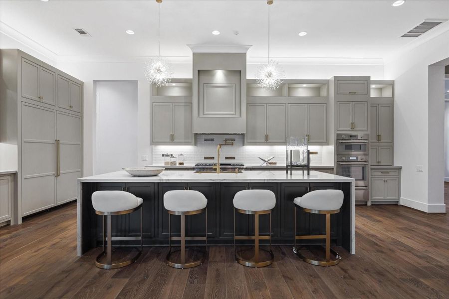Spacious kitchen with a gas stove and pot filler, huge island with additional storage and seating, and abundant countertop and storage space.