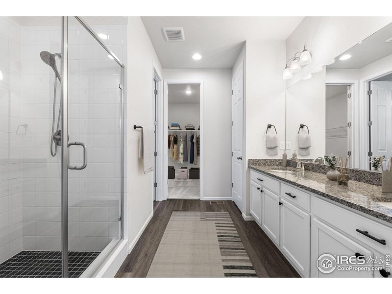 Main Level ensuite primary bathroom. This photo has been virtually staged to provide visual ideas for how furniture can be arranged in this area of the home.