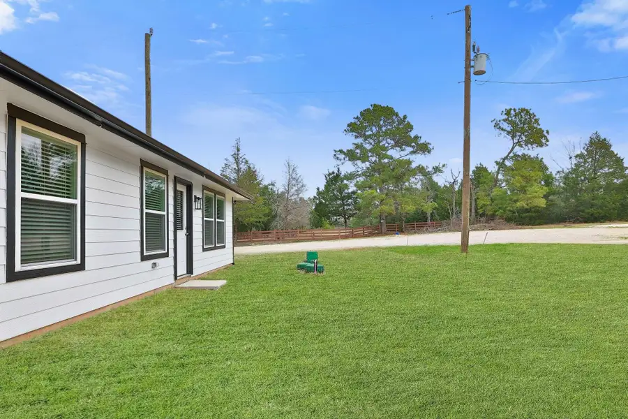 The property includes a newly sodded lawn with mature trees in the background, providing a serene and private setting.
