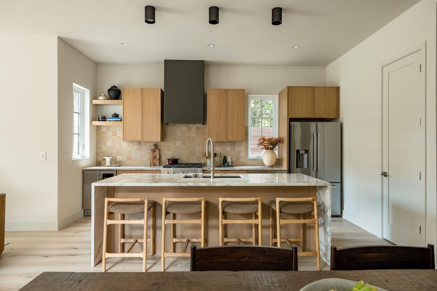 Natural wood cabinetry and a marble-waterfall island anchor this light-filled gourmet space. Natural wood cabinetry and a marble-waterfall island anchor this light-filled gourmet space.