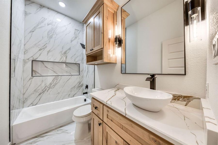 Full bath featuring light marble finish flooring, vanity, and shower / washtub combination