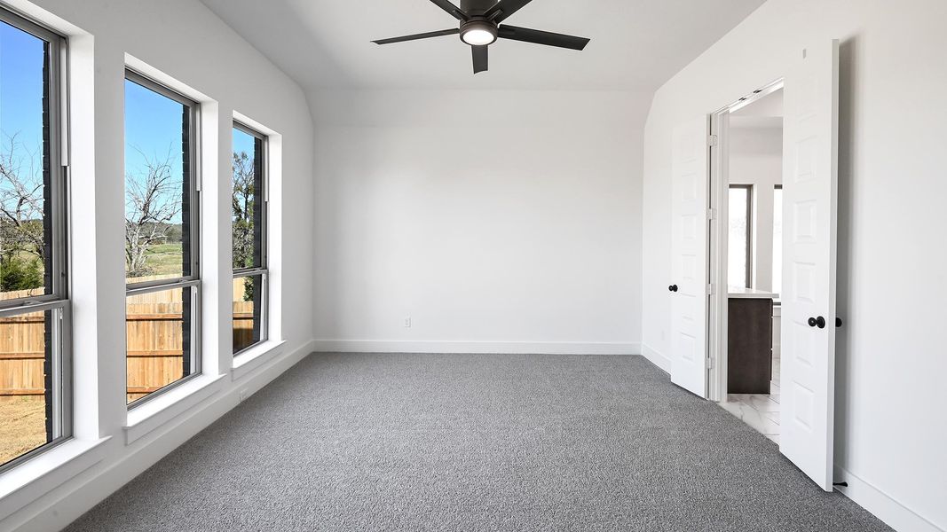 Carpeted spare room featuring a ceiling fan and baseboards