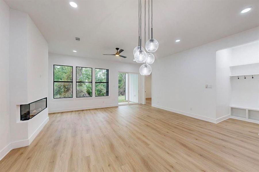 Unfurnished living room featuring a multi sided fireplace, light wood-type flooring, and ceiling fan