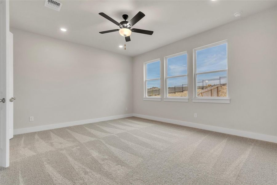A spacious room offers comfortable carpet flooring and abundant natural light.