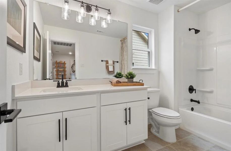 Full bath featuring toilet, shower / tub combo, vanity, and tile patterned floors