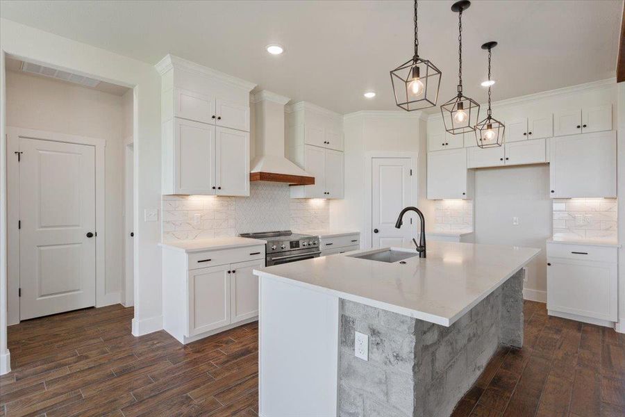 A well-appointed kitchen features a large island with sink, ample cabinetry, and modern pendant lighting.