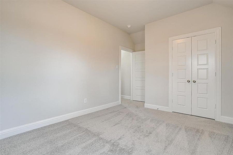 Unfurnished bedroom with a closet, carpet flooring, and vaulted ceiling