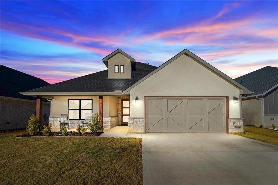 View of front of property with a porch, concrete driveway, stucco siding, a garage, and stone siding