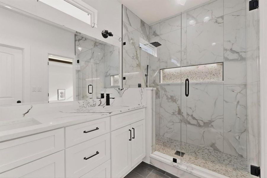 Bathroom featuring double vanity and a marble finish shower Bathroom featuring double vanity and a marble finish shower