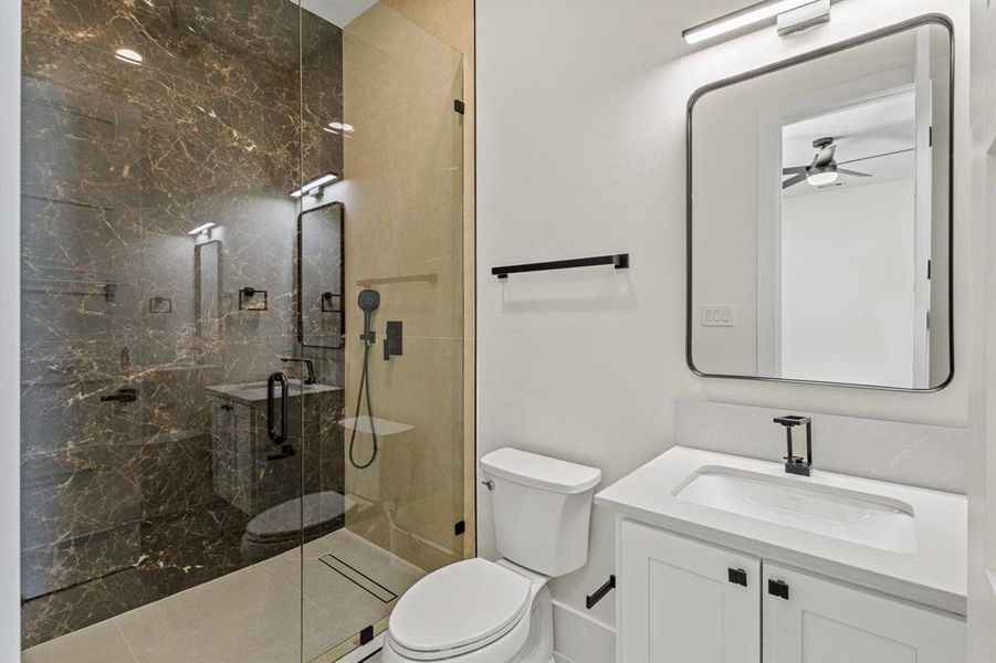 Bathroom featuring a marble finish shower, toilet, a ceiling fan, and vanity