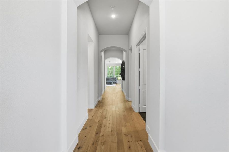 Hallway featuring wood-finish flooring, recessed lighting, and arched doorways Hallway featuring wood-finish flooring, recessed lighting, and arched doorways