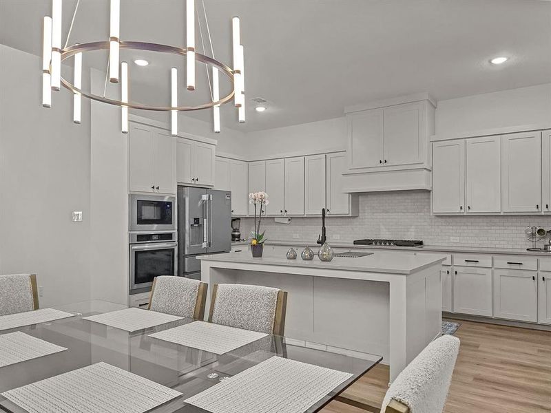 Kitchen with decorative light fixtures, white cabinetry, a center island, a chandelier, and appliances with stainless steel finishes