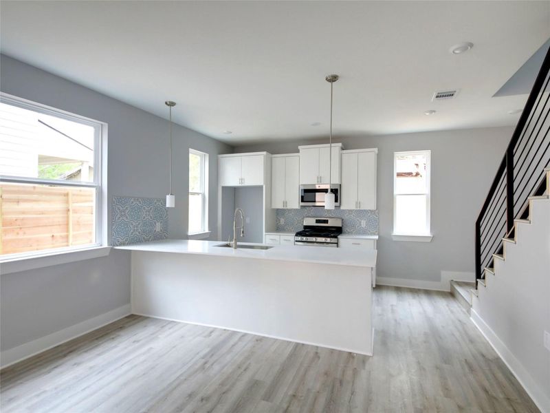 Kitchen featuring white cabinets, appliances with stainless steel finishes, a peninsula, and pendant lighting