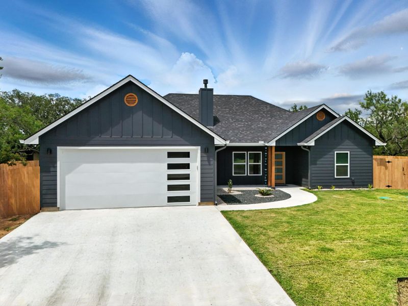 View of front of house with board and batten siding, a garage, driveway, and a shingled roof