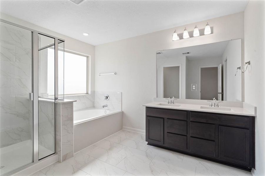 This primary bathroom is definitely move-in ready! Featuring a walk-in shower with tile surround, stained cabinets with light countertops, spacious walk-in closet with shelving, high ceilings, custom paint, sleek and dark modern finishes.