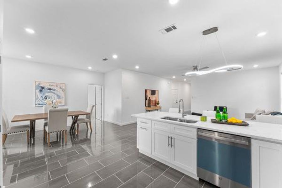 Kitchen featuring open floor plan, stainless steel dishwasher, white cabinets, hanging light fixtures, and recessed lighting Kitchen featuring open floor plan, stainless steel dishwasher, white cabinets, hanging light fixtures, and recessed lighting