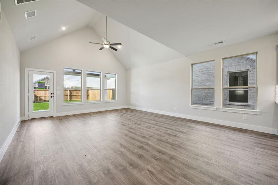 Unfurnished living room featuring ceiling fan, high vaulted ceiling, and light hardwood / wood-style floors