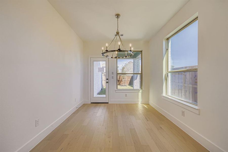 Unfurnished dining area featuring light wood-type flooring and a chandelier Unfurnished dining area featuring light wood-type flooring and a chandelier