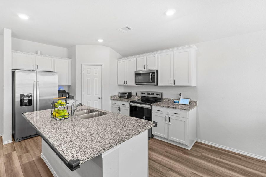 A well-lit culinary space featuring an island with ample counter space and modern appliances. A well-lit culinary space featuring an island with ample counter space and modern appliances.