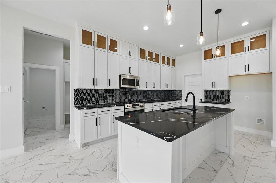 Kitchen with a sink, stainless steel microwave, baseboards, oven, and light marble finish floors Kitchen with a sink, stainless steel microwave, baseboards, oven, and light marble finish floors