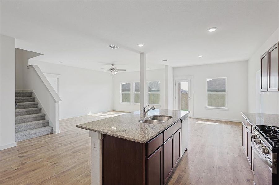 Kitchen featuring a wealth of natural light, sink, light stone counters, and light hardwood / wood-style flooring