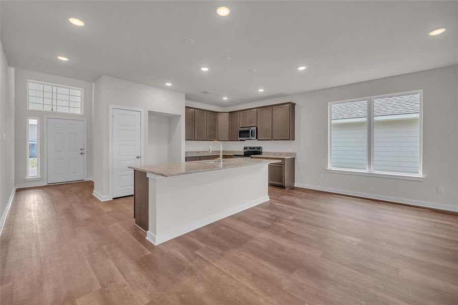 Kitchen featuring recessed lighting, light stone countertops, a kitchen island with sink, stainless steel appliances, and light wood-style floors Kitchen featuring recessed lighting, light stone countertops, a kitchen island with sink, stainless steel appliances, and light wood-style floors