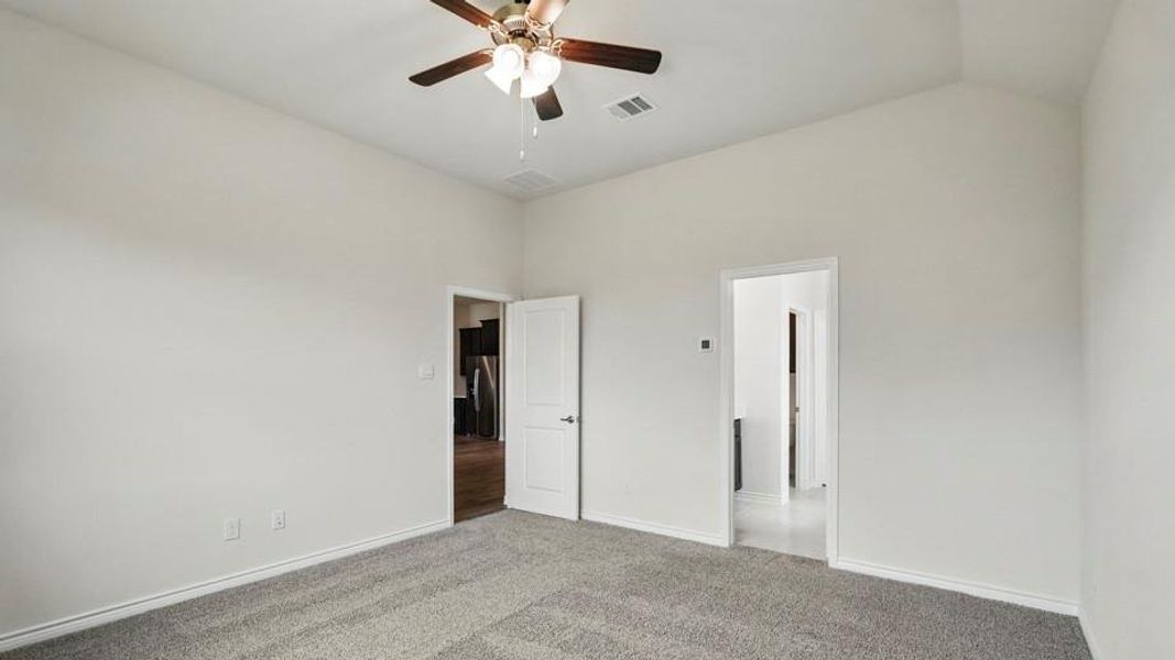 Carpeted interior room with vaulted ceilings and a ceiling fan with light fixture