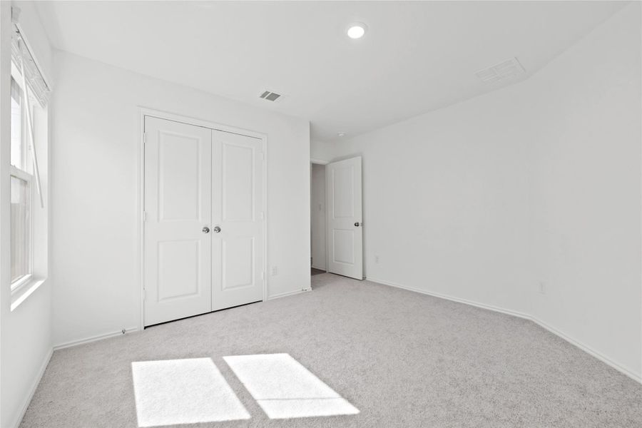 Unfurnished bedroom with light carpet and a closet