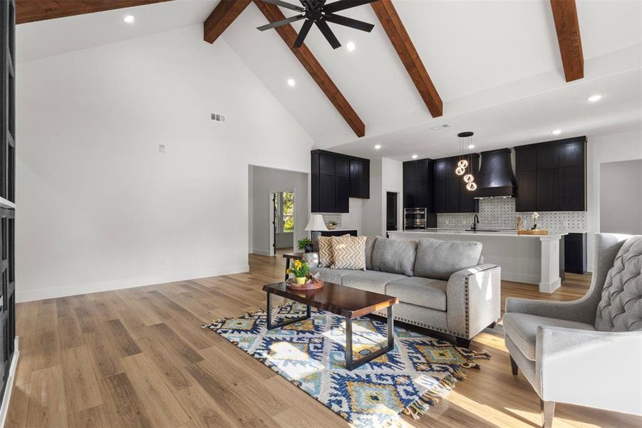Living area featuring beam ceiling, recessed lighting, high vaulted ceiling, light wood finished floors, and ceiling fan