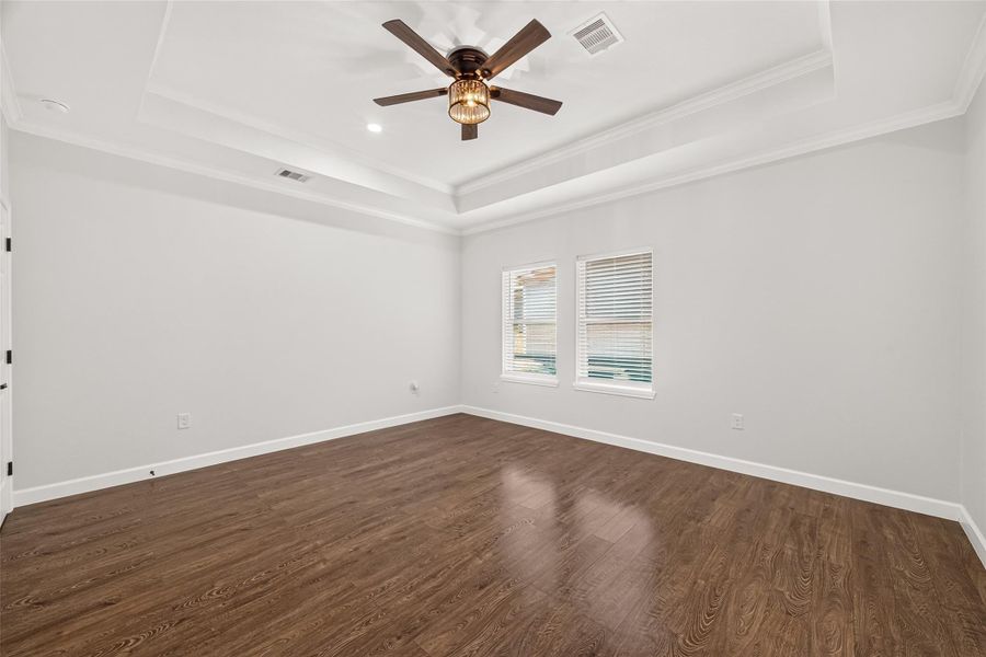 Generously sized primary bedroom with beautiful natural light and warm flooring.