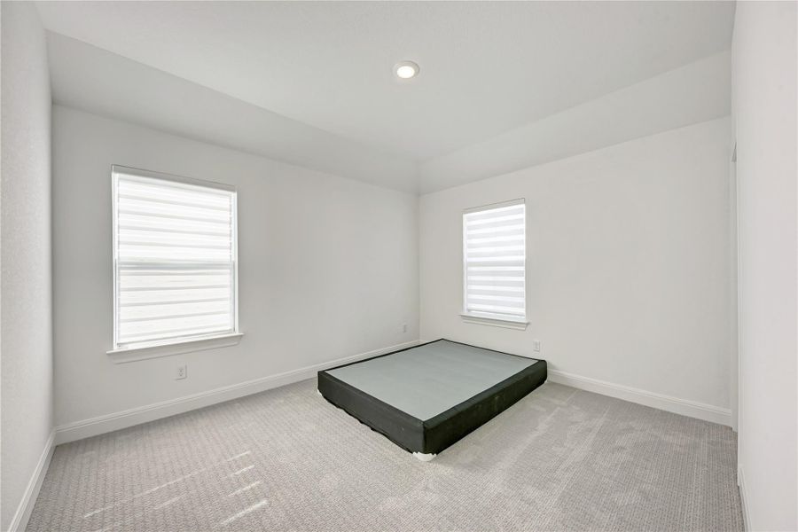 Room featuring two windows with horizontal blinds, light-colored carpeting, a recessed ceiling light, and crisp white walls