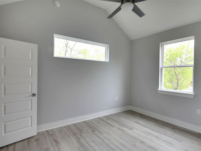Unfurnished room featuring vaulted ceiling, plenty of natural light, light wood-type flooring, and a ceiling fan