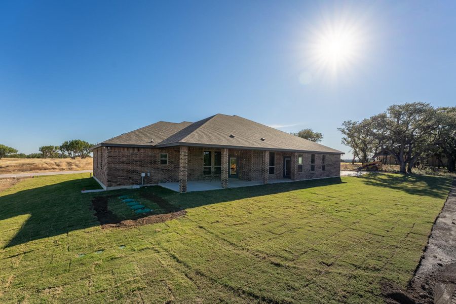 Back of property with brick siding, a lawn, and a patio area Back of property with brick siding, a lawn, and a patio area