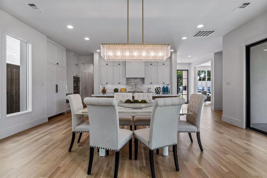 Dining space with sink, light wood-type flooring, and a notable chandelier