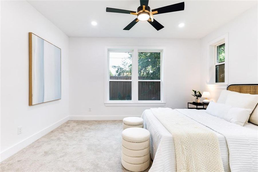 Carpeted bedroom with multiple windows and ceiling fan